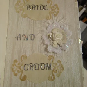 Wedding-1 A cream-coloured fabric wedding album with Latin phrases, featuring photo mats, pockets for keepsakes, and blog spots for personal notes, designed to preserve cherished memories in a timeless and functional way.