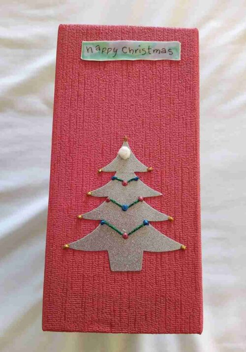 Xmas1 showing the spine covered in red cushioned paper with a gold tree and Happy Christmas tag.
