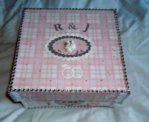 Wedding-4 A pink and cream chequered, embellished box, featuring bling accents along the top and sides. The box is personalized with the bride and groom's initials, and a pair of 3D white doves is elegantly placed at the centre. Embellished Photo Album Box