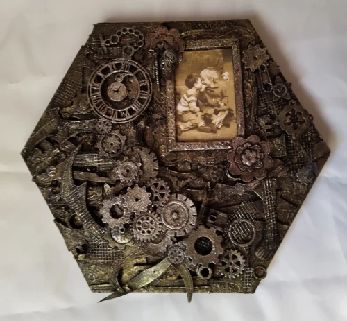 A Moment in Time-1 Mixed media artwork featuring a sepia photograph of a young boy leaning in to kiss a giggling girl, beside a small clock frozen at 9:05 p.m., surrounded by textured layers of paper, cogs, and found objects evoking themes of memory and time.