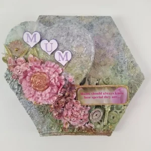 Mixed‑media canvas titled Special Mum with a raised heart reading “MUM,” pink flowers with a gold‑centred bloom, textured background, and a small sentiment tag in the bottom right.