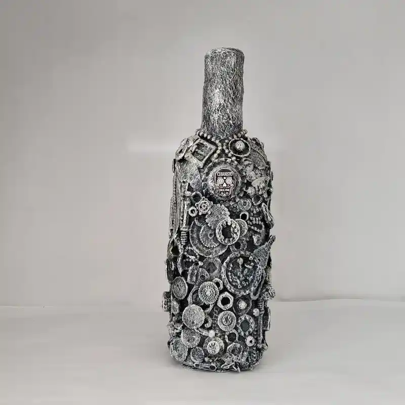 Metal assemblage bottle decorated with gears, bolts, and industrial components