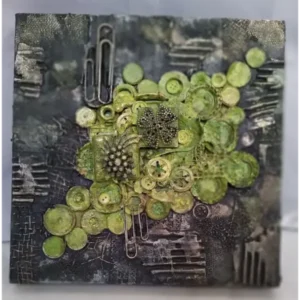 Grape Valley, a mixed‑media assemblage artwork featuring a green cluster of buttons and gears resembling grapes, set among layered metal, lace, and scrap materials.