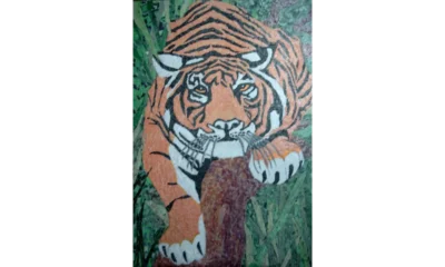 Tiger Tiger, a torn‑paper collage depicting an orange and black tiger crouched among green foliage, created from fragmented coloured paper pieces that form a textured, expressive composition.