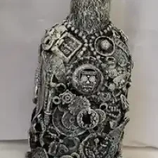 Bottle-1: Bottle-O-Rum, a mixed media bottle made covered with detritus of glass shards, small plastics and mixed metal pieces