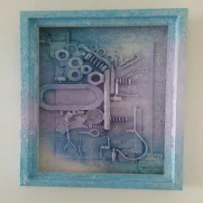 Hooked is a textured mixed media artwork featuring layers of acrylic paint, found objects like metal gears, and wire, and a steampunk-inspired design. The piece combines industrial and organic elements, creating a tactile, visually complex composition.